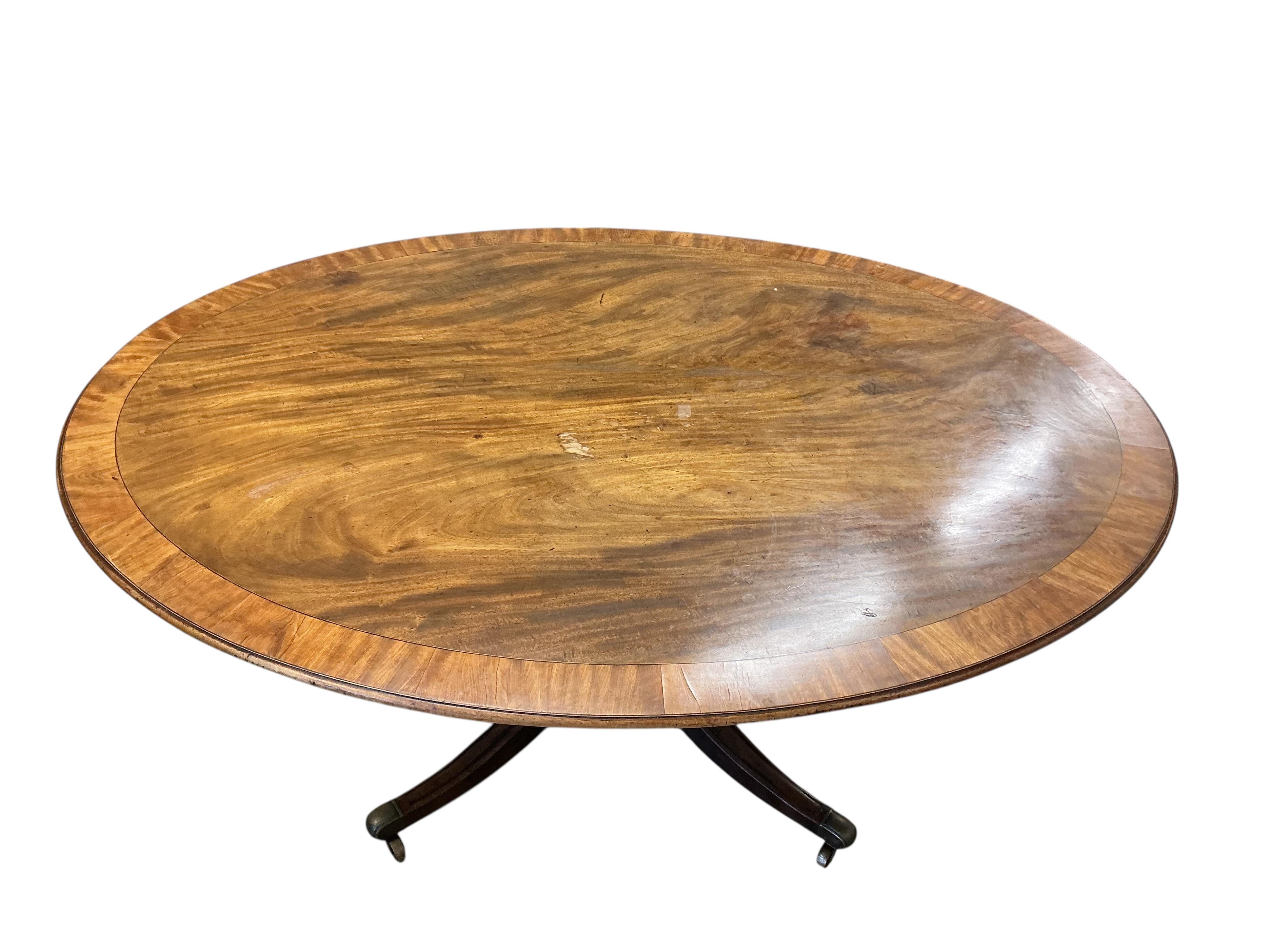 A George III banded mahogany oval tilt top dining table, width 160cm, depth 122cm, height 70cm